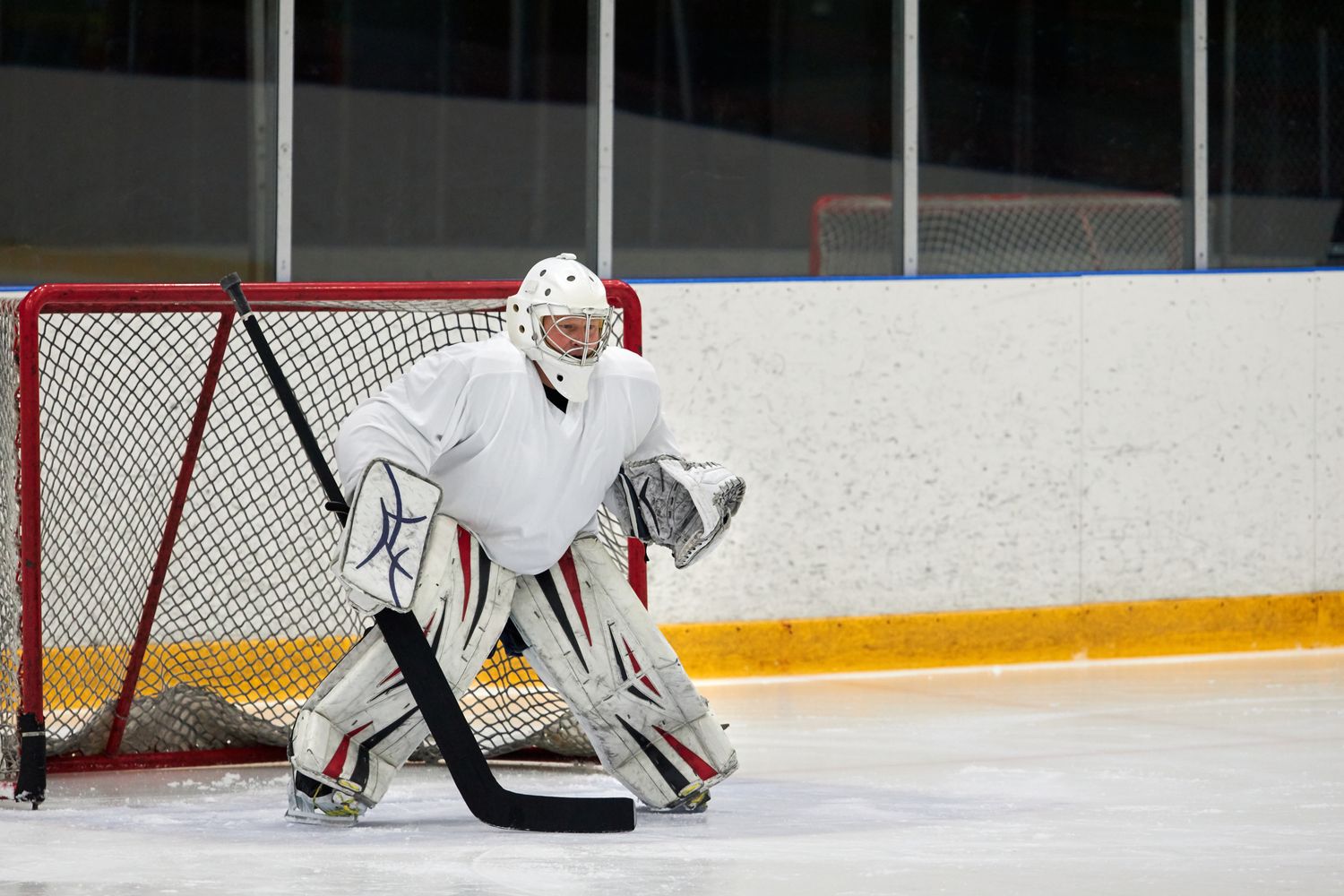 Gardien de hockey devant sa cage, crosse en main